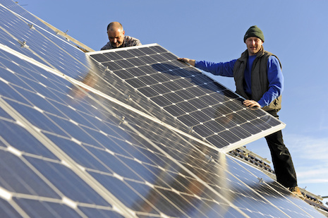 Zwei Arbeiter bei der Montage einer Photovoltaik-Anlage auf einem Hausdach